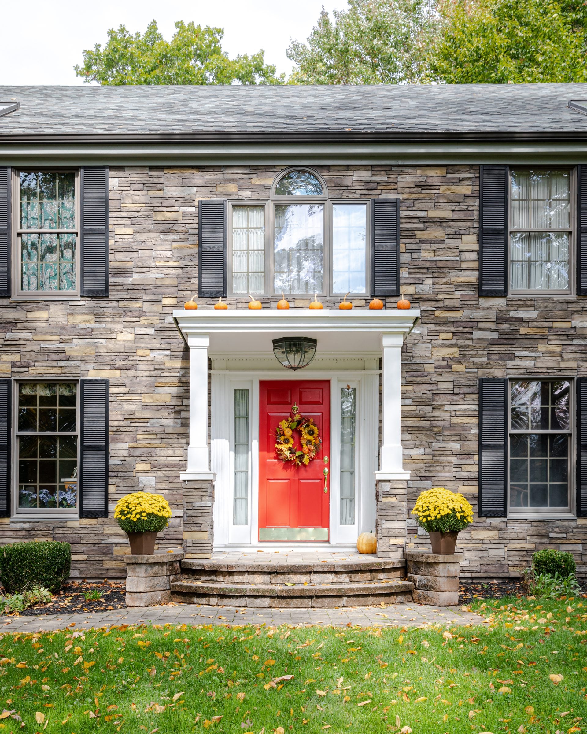Home facade clad in Plum Creek Versetta Stone with a red front door